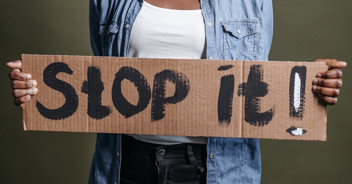 A woman holding stop it sign